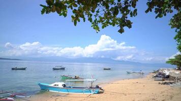 Boats Anchored on a Sandy Shore. A picturesque view of boats anchored on a sandy shore with a tranquil ocean and a mountain range in the distance. video