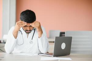 Closeup portrait, young depressed man healthcare practitioner holding face in despair photo