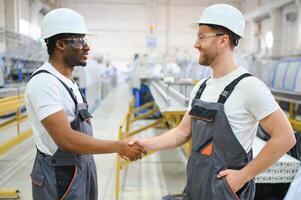 Two workers in production plant as team discussing, industrial scene in background photo