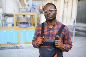 Portrait of industrial engineer. Smiling factory worker with hard hat standing in factory production line photo