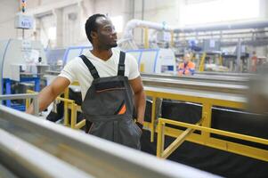 Portrait of African American male engineer in uniform and standing in industrial factory photo