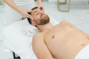 Handsome middle-aged man enjoying relaxing spa massage with oils photo