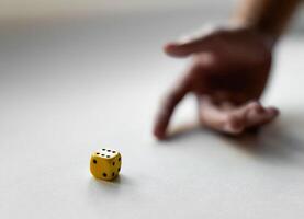 Hand in motion with yellow dice on a white surface capturing chance and luck photo