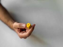 Close-up of hand holding a yellow dice for gaming and luck concepts photo