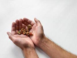 Hands gently holding colorful polyhedral dice on white background photo