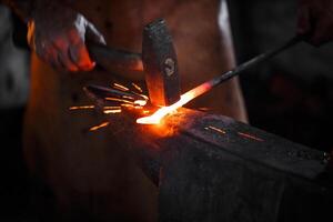 Blacksmith manually forging the molten metal photo