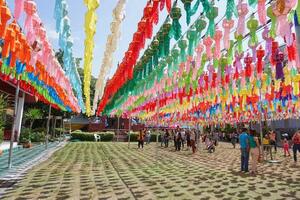 Lumphun city, TH 2019 - Colorful perspective view of Thai Lanna style lanterns to hang in front of the temple with people and tourists in hundred thousand lanterns festival. photo