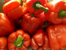 Closeup and crop heap of fresh red bells pepper for sale in the market fit to screen photo