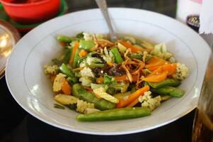 a bowl of stir fry vegetables with a fork in it photo