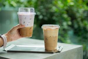 hand of woman holding a take-out iced coffee with taro milk on cement table photo