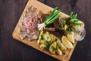 Sliced herring with potatoes and onions on wooden board photo