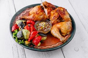 Roasted chicken with vegetables and sauce on rustic plate photo