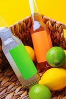 Two bottles resting in basket with lemons and limes on yellow background photo