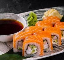 Fresh salmon sushi roll with soy sauce on dark slate photo
