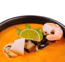 Spicy seafood soup in a bowl with lime garnish photo