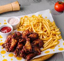 Crispy chicken wings and fries with dips on table photo