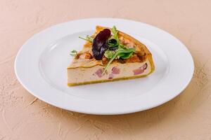 Slice of quiche lorraine resting on a white plate photo