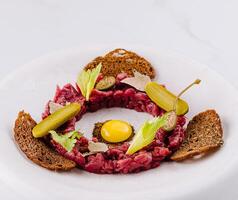 Deconstructed beef tartare with quail egg and rye bread photo
