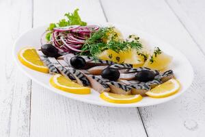 Sliced salted mackerel with potatoes and onions on white plate photo