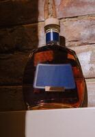 Bottle of cognac sitting on shelf with blank label and brick background photo