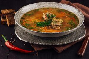 Bowl of chicken soup with vegetables and herbs sitting on rustic table photo