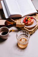 Glass of whisky with ice and bottle enjoying leisure time with book and dessert photo