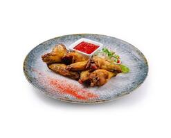 Crispy chicken wings served on modern plate with dipping sauce and garnish photo