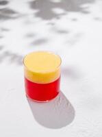 Two colored layered cocktail is standing on white table with shadows photo