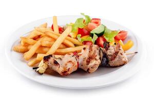Chicken shish kebab plate being served with french fries and salad photo
