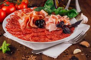 Delicious cold cuts platter with prosciutto and salami on wooden table photo