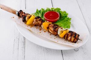 Grilled pork meat shish kebab served on pita bread with tomato sauce and salad photo