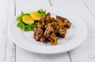 Delicious beef stew with potatoes and onions lying on white plate on white background photo