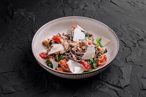 Black spaghetti with salmon, spinach and parmesan cheese lying on dark stone background photo