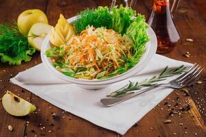 Fresh cabbage salad with apple slices and herbs on wooden table photo
