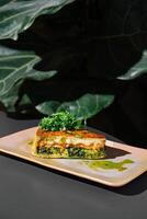 Delicious slice of quiche with salmon and spinach resting on plate photo