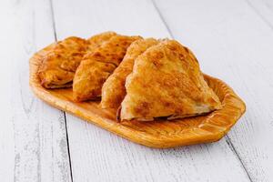 Delicious chebureki pastries resting on a wooden plate photo