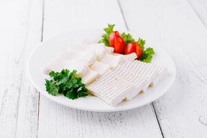 White cheese slices with cherry tomatoes and parsley on white plate photo