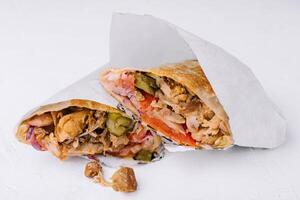 Delicious chicken shawarma lying on white background photo