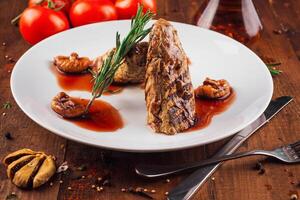 Grilled meat with figs and rosemary lying on a white plate photo