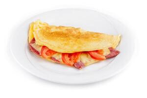 Folded omelette filled with cheese, ham and tomatoes on white plate photo