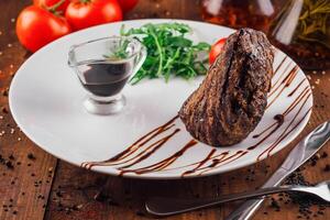 Grilled beef steak with sauce, arugula, tomato and spices on white plate photo