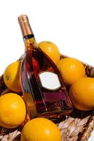 Bottle of liquor resting on oranges in a basket photo