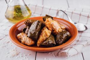 Traditional dolma stuffed grape leaves with rice and spices on rustic table setting photo