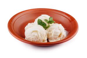 Three scoops of vanilla ice cream melting in rustic bowl with mint garnish photo