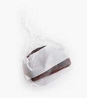 Freshly baked chocolate pound cake wrapped in plastic on white background photo
