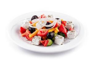 Greek salad with feta cheese, olives, and vegetables on white plate photo