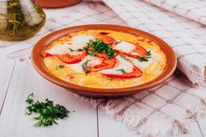 Delicious italian gnocchi with mozzarella and tomatoes being served on a white wooden table photo