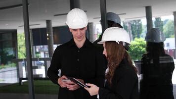 Female carpenter apprentice with her colleague. Guy and girl at a construction site, builders foreman video