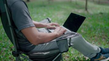 Programmer is writing code, typing on laptop keyboard, development, graph analysis and typing on a laptop, work stress, working online, anxiety, working in a park, office syndrome. video