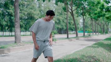 Asian tan man feel exhausted and tiredpain while exercise in park. Attractive sportsman has difficulty breath clutching chest from acute pain while practice workout for health in park. video